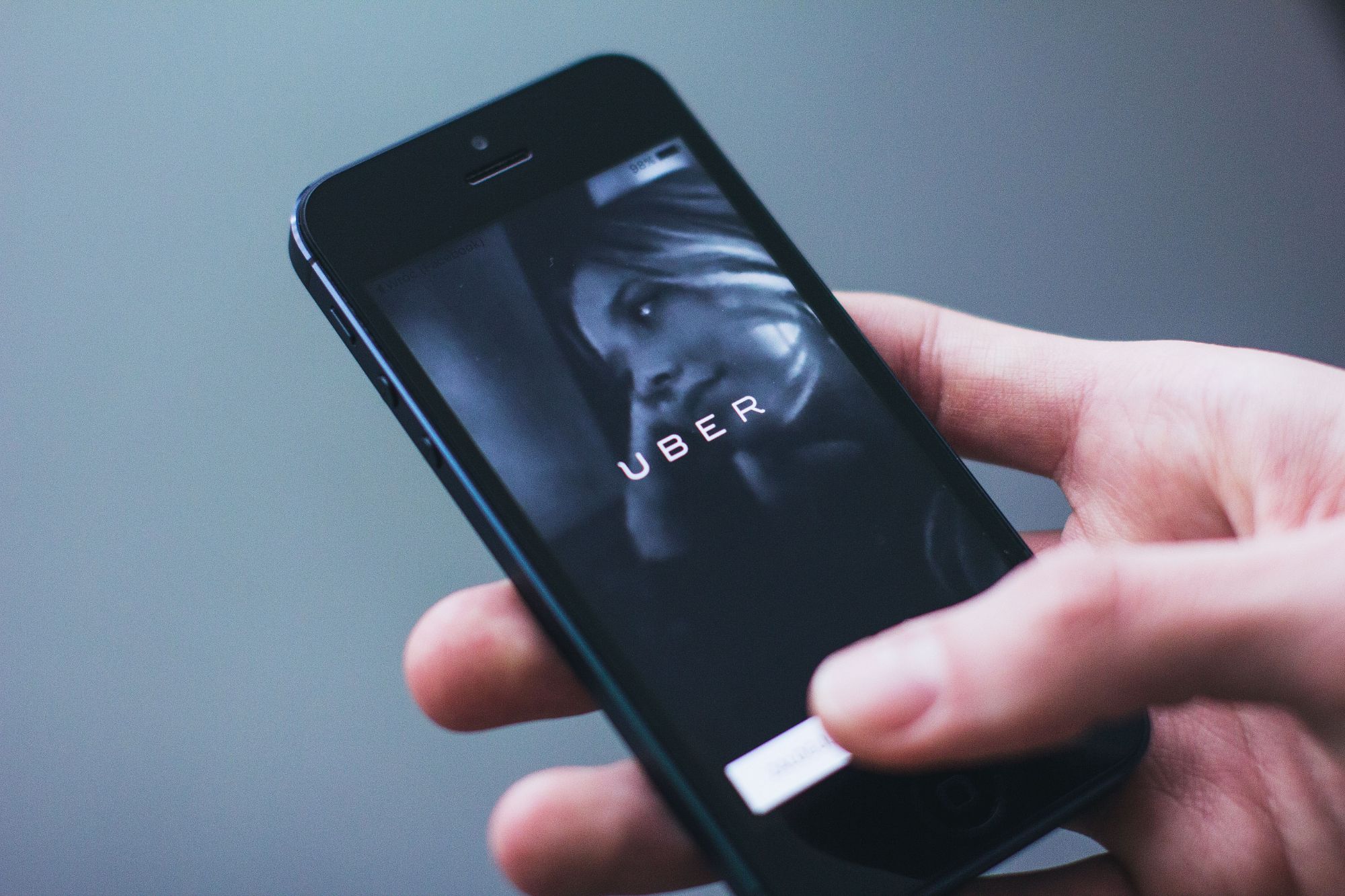 A hand holding a smartphone showing the Uber app